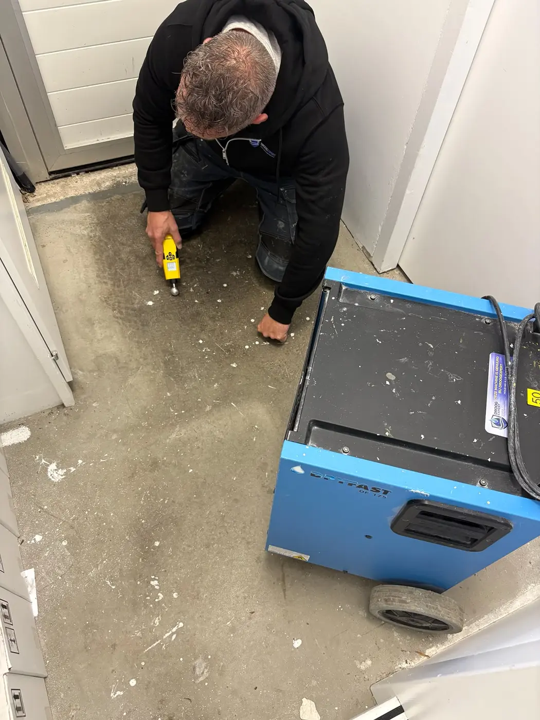 Droogexpert voert een vochtmeting uit in een vloer op een projectlocatie in Amsterdam